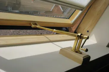 A telescopic screwjack with a handle installed on a pitched roof window